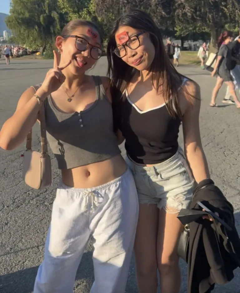 Two friends with Maake healthy snack stickers on their foreheads at a summer pop-up, throwing peace signs