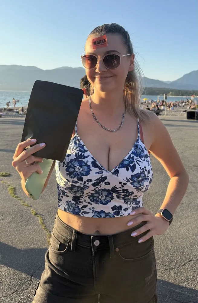 A smiling customer at Kits Beach holding a Maake pouch